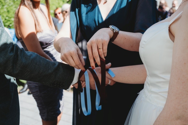 Wrap Handfasting Anleitung Schritt 3: Das zweite Band des WRAPs wird gelegt von der Schwester der Braut