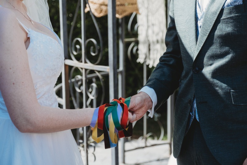 Wrap Handfasting Anleitung Schritt 6: Braut und Bräutigam fassen alle Bänder mit ihrer jeweils rechten Hand.