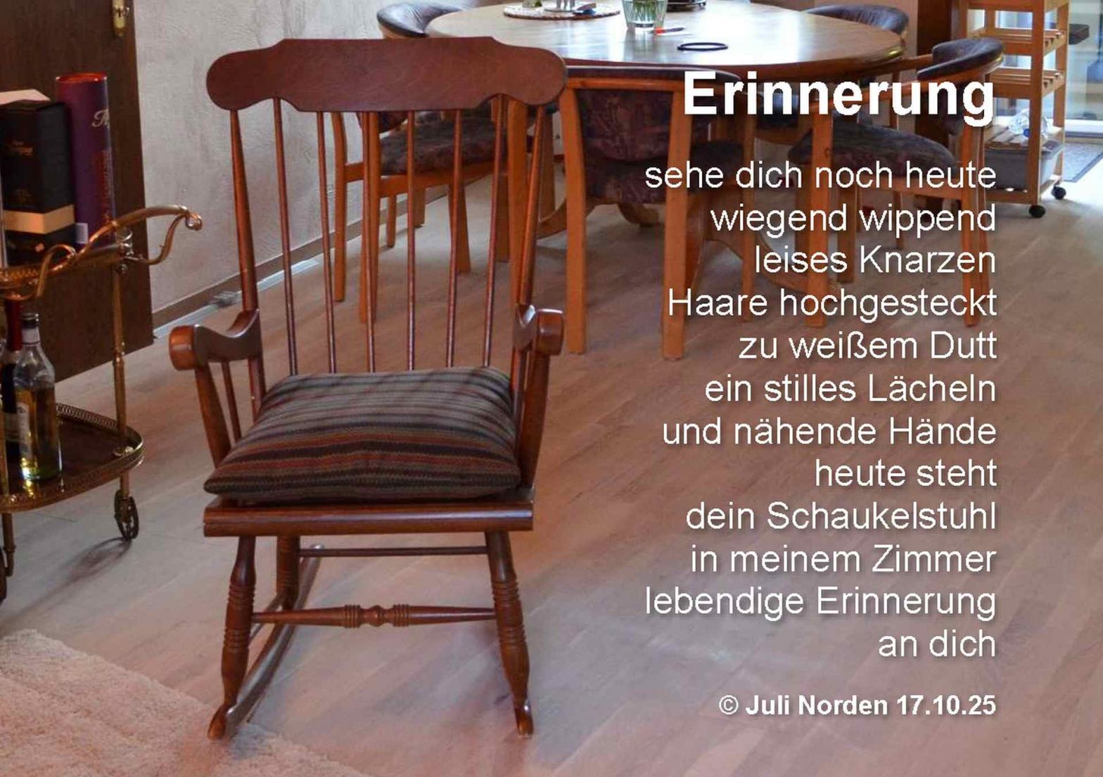 Schaukelstuhl aus dunklem Holz in einem Wohnzimer auf Parkettboden. Daneben das Gedicht "Erinnerung" von Juli Norden
