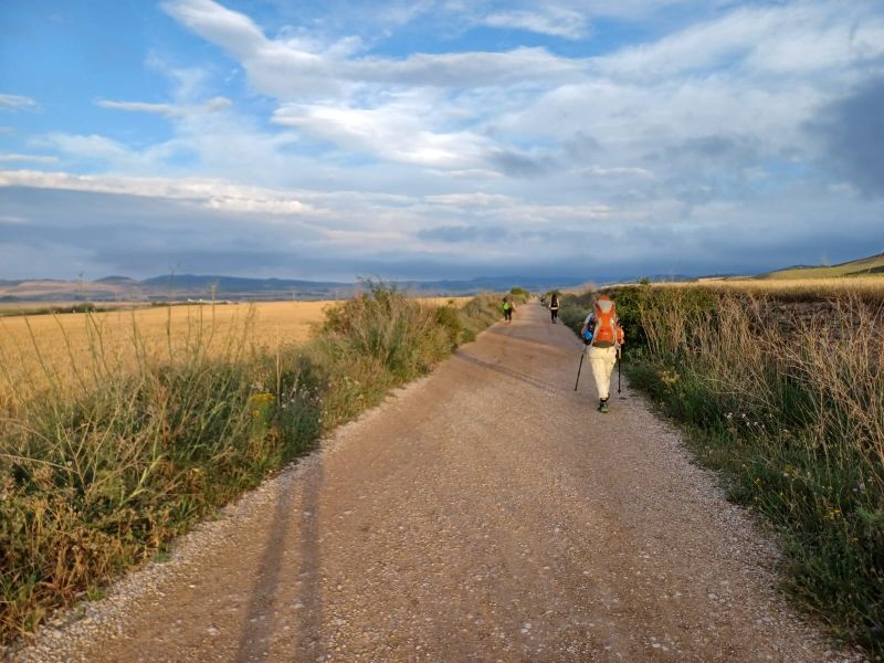 Wanderer auf dem Camino in herbstlicher Landschaft, blauer Himmel mit Wolken