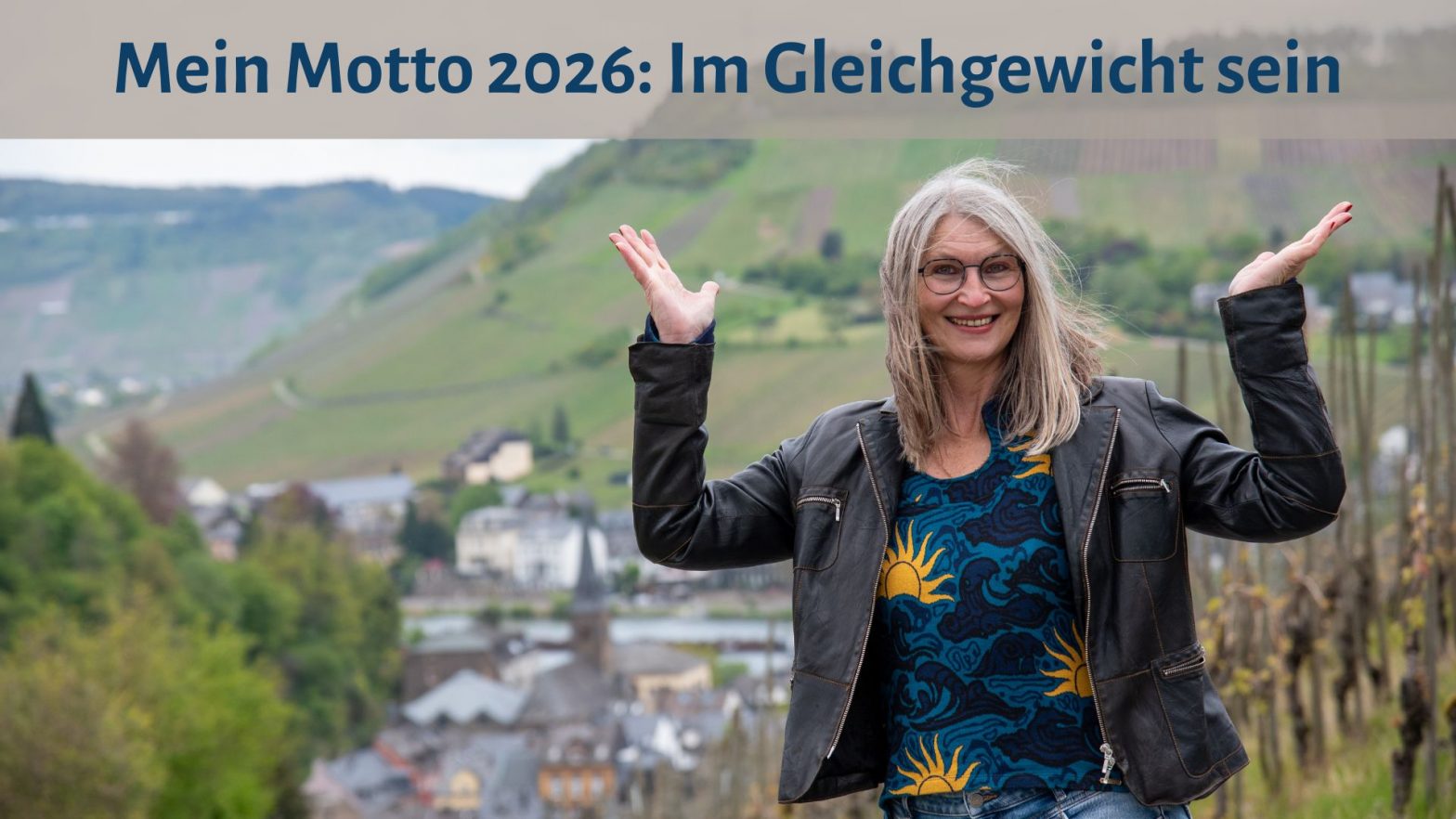 Gabi Kremeskötter steht mit erhobenen Händen vor den Weinbergen an der Mosel, ihre Hände bilden eine Waage, darüber der Text: "Mein Motto 2026: Im Gleichgewicht sein"