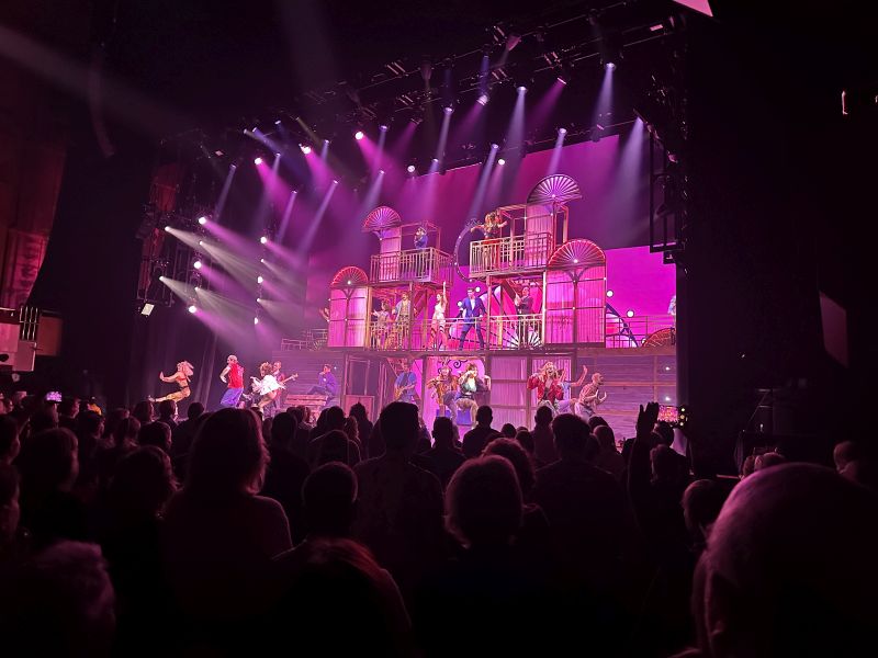 Finale des Musicals Pretty Woman in der Alten Oper Frankfurt, die Bühne ist pink erleuchtet und das gesamte Ensemble tanzt und singt.