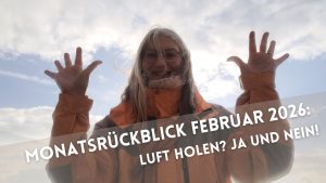 Langhaarige, lächelnde Frau in Winterjacke mit hoch hochgehaltenen Händen und abgespreitzten Fingern vor wolkigem Himmel.