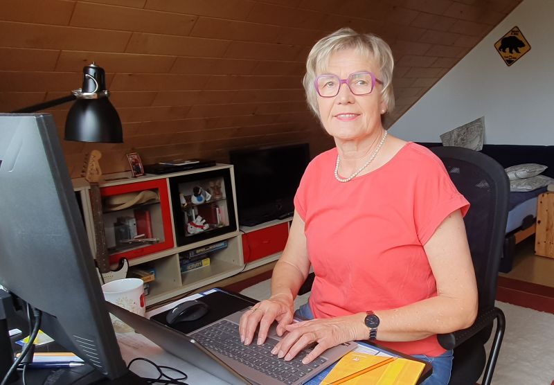 Autorin Elke Ruhe an ihrem Schreibtisch, sie sitzt am Laptop und lächelt in die Kamera.