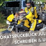 Frau auf gelbschwarzer BMW F800R in gelbschwarzer Dainese-Leder-Kombi, darunter der Text: Monatsrückblick Juli 2026: Schreiben & Urlaub