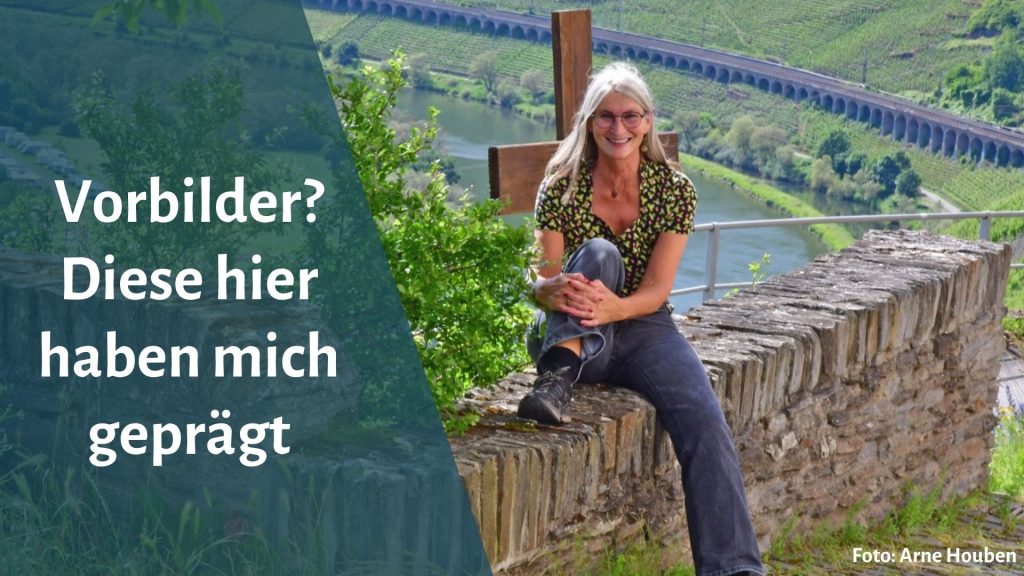 Frau sitzt auf Natursteinmauer, im Hintergrund das Moseltal bei Reil