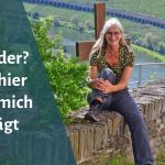 Frau sitzt auf Natursteinmauer, im Hintergrund das Moseltal bei Reil
