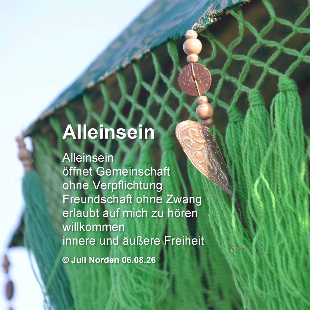 Ausschnitt eines grünen Sonnenschirms mit Herzdeko, darauf das Gedicht "Alleinsein" von Juli Norden