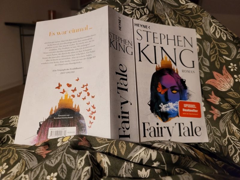 Taschenbuch Fairy Tale von Stephen King, aufgeschlagen auf einer Bettdecke mit dem Text nach unten